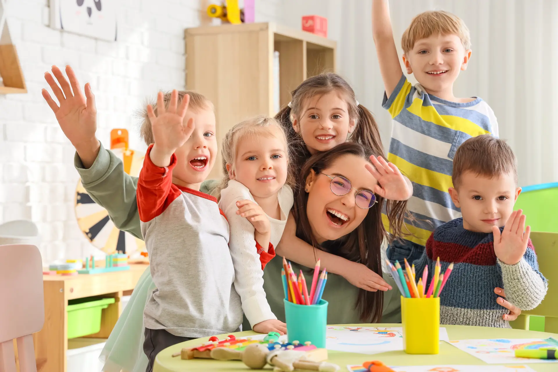 A teacher smiling with a group of preschool children
